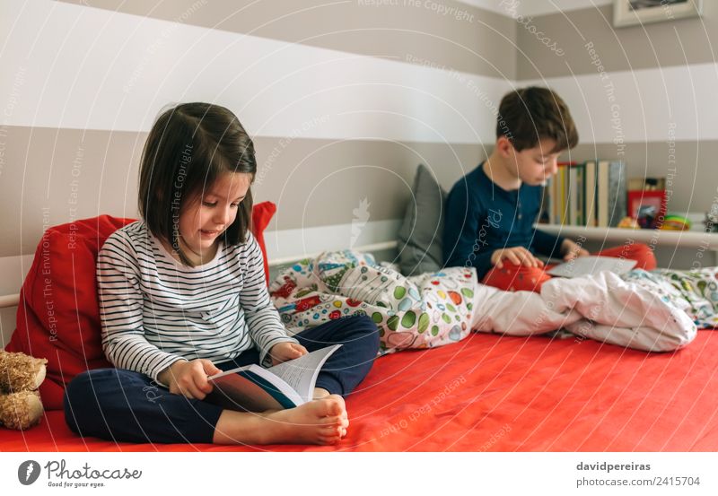 Mädchen und Junge lesen Buch auf dem Bett sitzend Lifestyle schön Windstille Schlafzimmer Kind Schule Mensch Frau Erwachsene Mann Schwester