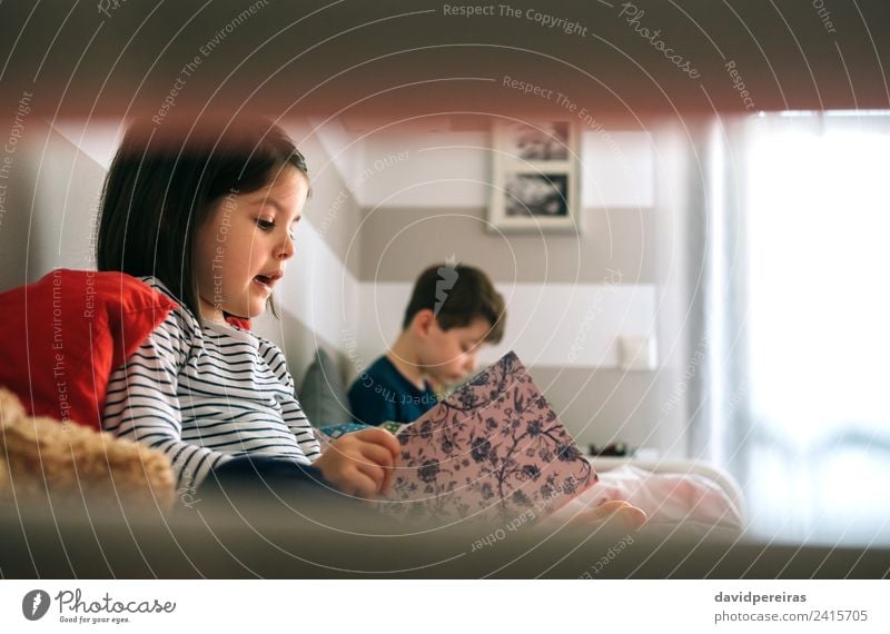 Mädchen und Junge lesen jeweils ein Buch auf dem Bett sitzend Lifestyle schön Windstille Schlafzimmer Kind Schule Mensch Frau Erwachsene Mann Schwester