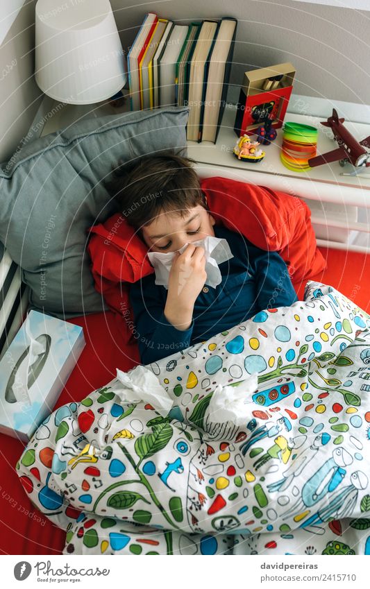Kaltes Kind auf dem Bett liegend Lifestyle Krankheit Lampe Schlafzimmer Mensch Junge Mann Erwachsene Buch Fluggerät Spielzeug authentisch Müdigkeit lügen kalt