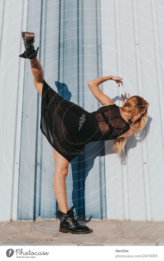 Blonde weiße Frau in schwarzem Kleid, die einen zeitgenössischen Tanz aufführt und dabei das Bein hochhebt. Lifestyle Körper Tanzen Sport Mensch Erwachsene