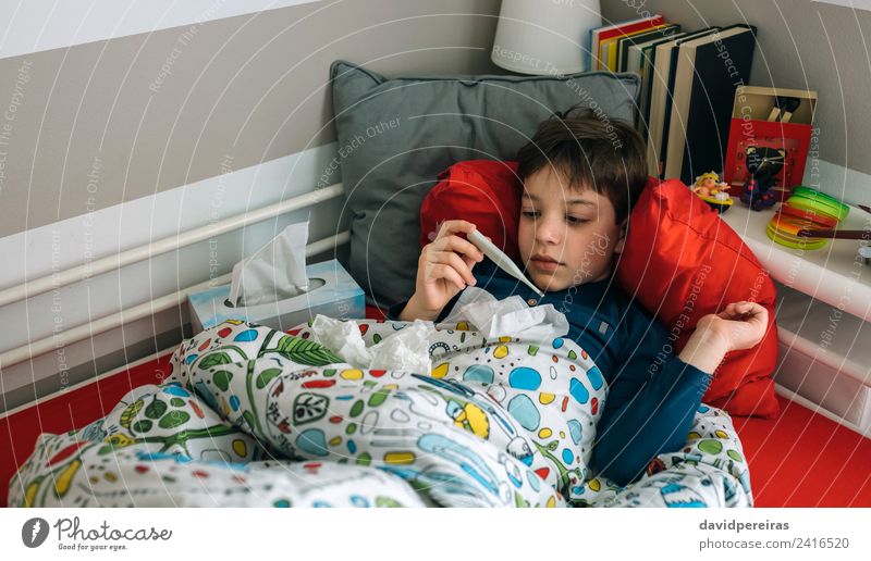 Kaltes Kind schaut auf das Thermometer. Lifestyle Krankheit Lampe Schlafzimmer Mensch Junge Mann Erwachsene Kindheit Buch Spielzeug authentisch Müdigkeit lügen
