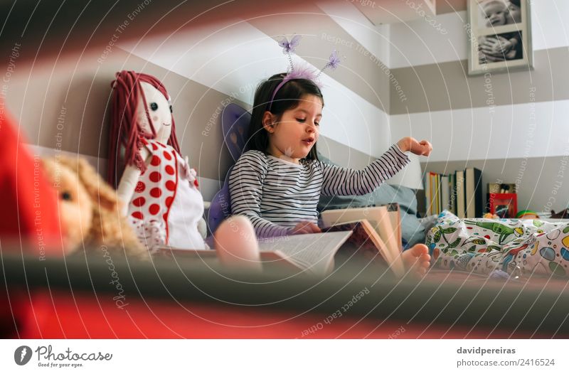 Mädchen verkleidet, die ihrer Puppe ein Buch vorliest. Lifestyle Glück Spielen lesen Schlafzimmer Kind Mensch Frau Erwachsene Freundschaft Schmetterling Flügel
