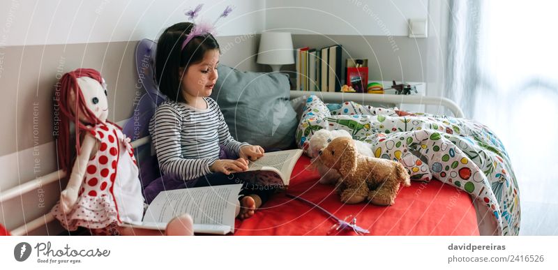 Kleines Mädchen sitzt auf dem Bett und liest ihrem Spielzeug ein Buch vor schön Spielen lesen Schlafzimmer Kind Lehrer sprechen Mensch Frau Erwachsene