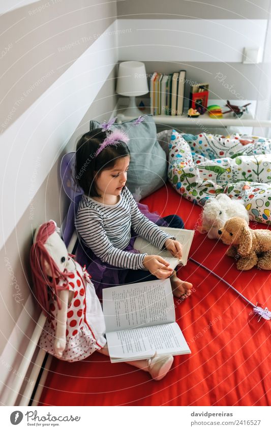 Kleines Mädchen sitzt auf dem Bett und liest ihrem Spielzeug ein Buch vor Lifestyle Freude schön Spielen lesen Schlafzimmer Kind Lehrer sprechen Mensch Frau