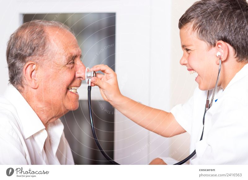 Ein Kind untersucht seinen Großvater mit einem Stethoskop. Lustiges Spiel Gesicht Gesundheitswesen Krankheit Medikament Spielen Beruf Arzt Krankenhaus Karriere
