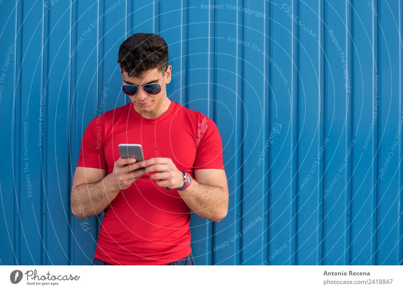 Rot sozial auf blauer Wand lesen Telefon PDA Mensch Mann Erwachsene Sonnenbrille brünett berühren rot 20-25 Jahre alt 20s 30 Jahre alt attraktiv Tür Latein