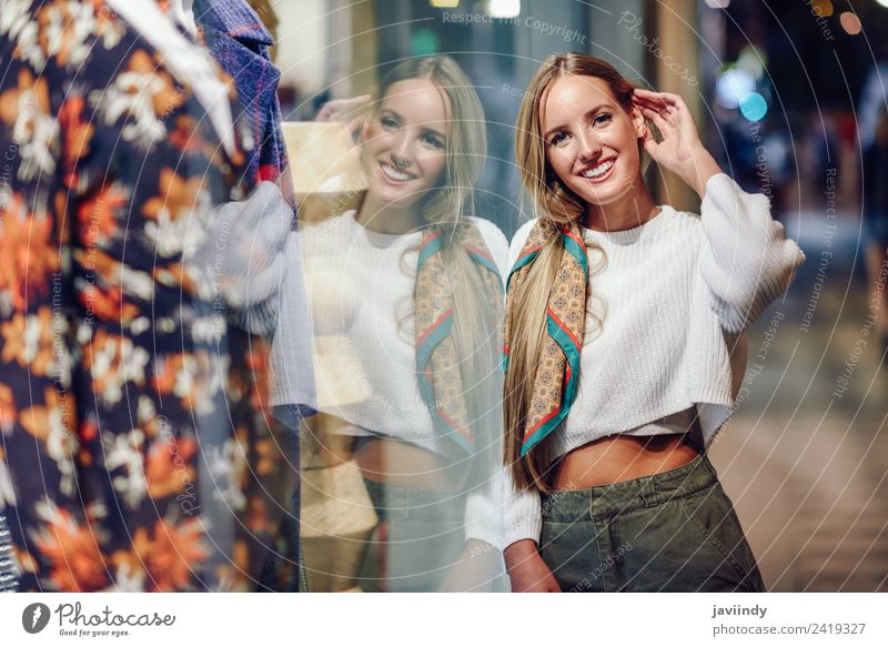 Blondes Mädchen trägt weißen Pullover lächelnd auf der Straße mit defokussierten Stadt Lichter im Hintergrund Lifestyle kaufen Stil Glück schön Haare & Frisuren