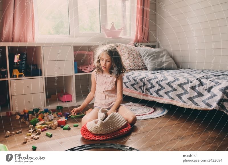 Kind Mädchen reinigt ihr unordentliches Zimmer und legt Spielzeug in den Korb. Lifestyle Spielen Schlafzimmer Kindergarten Holz bauen authentisch modern