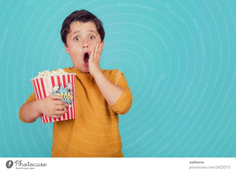 überraschter Junge mit Popcorn auf blauem Hintergrund Lebensmittel Ernährung Essen Fastfood Lifestyle Freude Freizeit & Hobby Mensch maskulin Kind Kleinkind