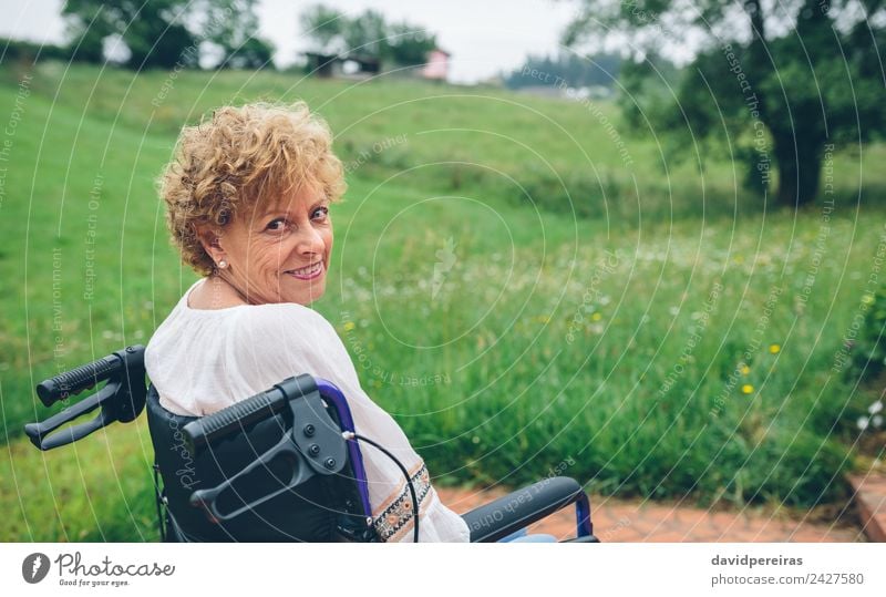 Lächelnde Seniorin im Rollstuhl Glück Gesundheitswesen Erholung Garten Ruhestand Mensch Frau Erwachsene Großmutter Natur Pflanze Baum Gras alt sitzen