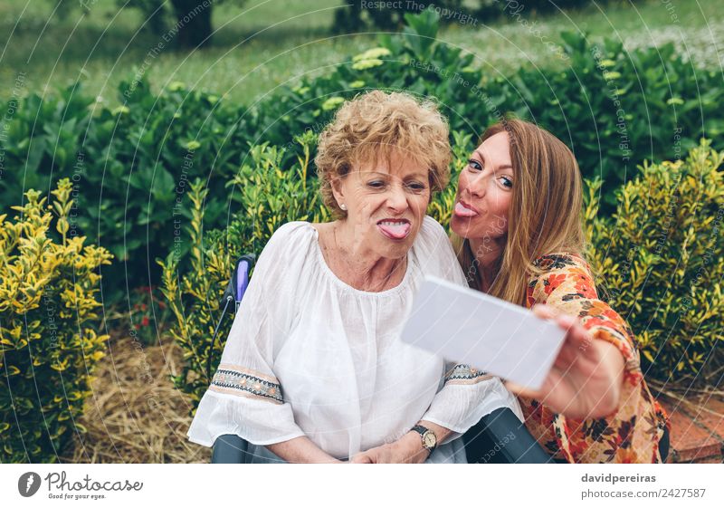 Frau nimmt Selfie mit älterer Mutter im Rollstuhl Lifestyle Freude Glück Gesundheitswesen Garten PDA Mensch Erwachsene Großmutter Familie & Verwandtschaft Natur