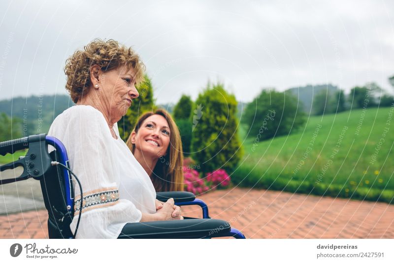 Ältere unzufriedene Frau im Rollstuhl mit ihrer Tochter Lifestyle Gesundheitswesen Erholung Garten sprechen Mensch Erwachsene Mutter Großmutter