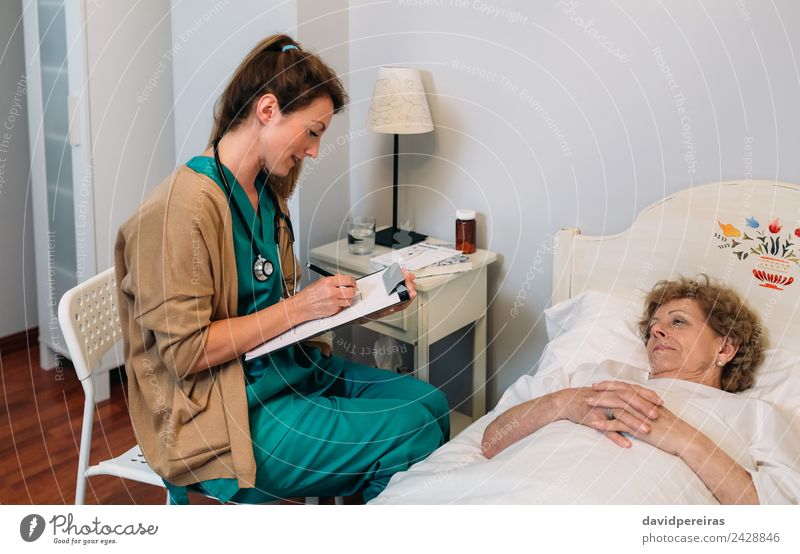 Ärztin füllt Fragebogen für älteren Patienten aus Gesundheitswesen Behandlung Krankheit Medikament Haus Lampe Stuhl Arzt Krankenhaus Mensch Frau Erwachsene alt