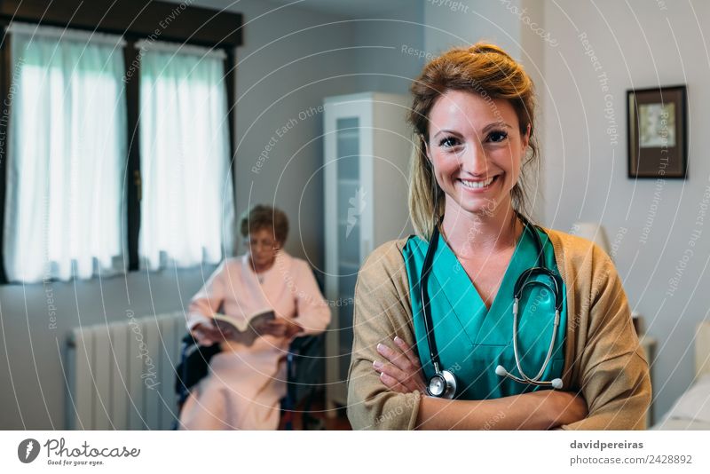 Hübsche Ärztin, die in einer Altersklinik posiert. Glück Gesundheitswesen Krankheit Erholung lesen Schlafzimmer Arzt Krankenhaus Mensch Frau Erwachsene alt