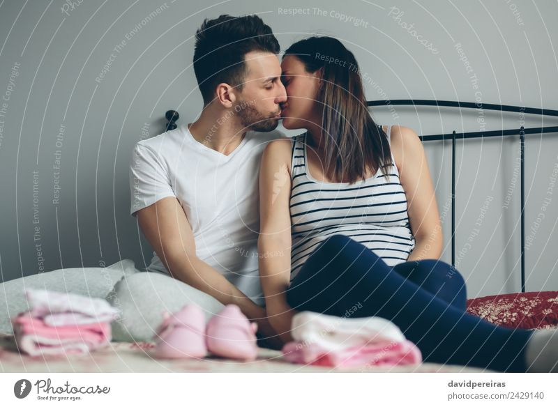 Ein Mann, der seine schwangere Frau küsst. schön Mensch Baby Erwachsene Mutter Familie & Verwandtschaft Paar Bekleidung Schuhe Vollbart Küssen Liebe sitzen