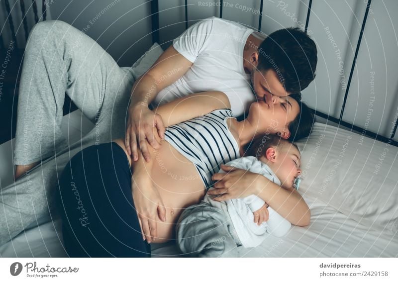Schwanger, die ihre Partnerin mit ihrem Sohn küsst. Glück schön Leben Erholung Schlafzimmer Kind Mensch Baby Kleinkind Frau Erwachsene Mann Eltern Mutter Vater