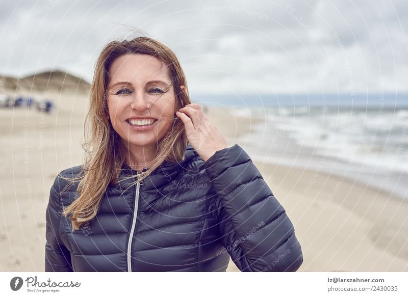 Attraktive Frau an einem windgepeitschten Strand Gesicht Freizeit & Hobby Freiheit Meer Erwachsene 1 Mensch 45-60 Jahre Sand Wolken Herbst Unwetter Wind Küste