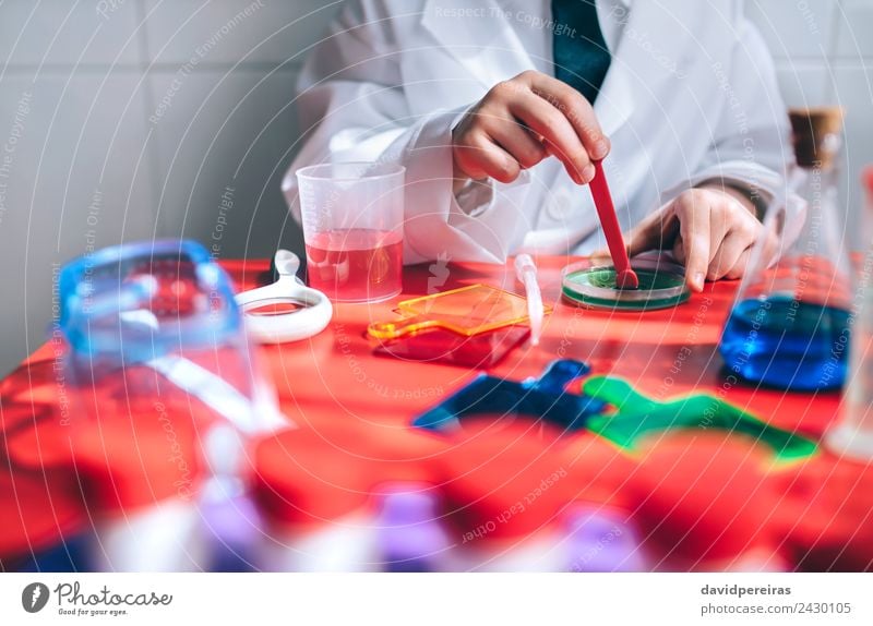 Jungenhände spielen um Chemiker zu werden mit bunten Flüssigkeiten. Flasche Löffel Spielen Wohnung Tisch Wissenschaften Kind Klassenraum Labor Mensch Kindheit