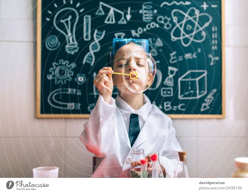 Kind, das Seifenblasen gegen eine gemalte Tafel macht. Freude Glück Spielen Wohnung Wissenschaften Schule Klassenraum Labor Mensch Junge Kindheit authentisch