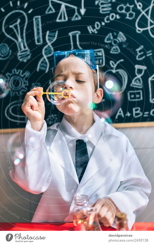 Kind, das Seifenblasen gegen eine gemalte Tafel macht. Flasche Freude Glück Spielen Wohnung Tisch Wissenschaften Schule Klassenraum Labor Mensch Junge Kindheit