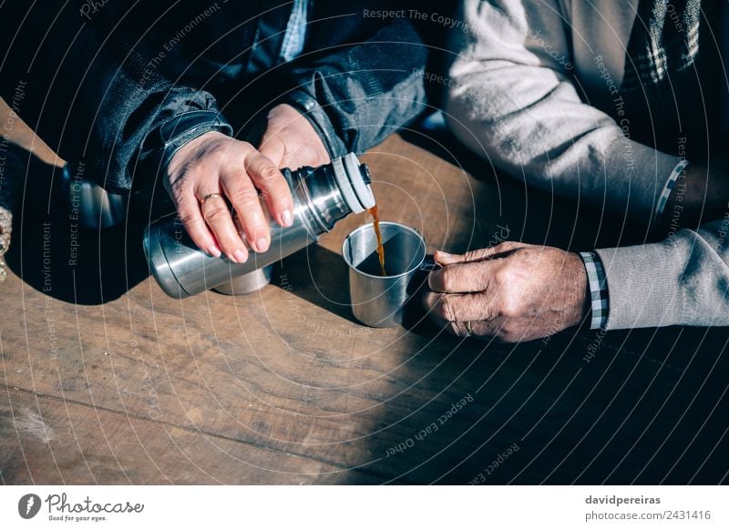 Senior Paar Hände gießen Kaffee aus der Thermoskanne. trinken Tee Lifestyle Erholung Freizeit & Hobby Tisch Mensch Frau Erwachsene Mann Hand Holz Metall alt