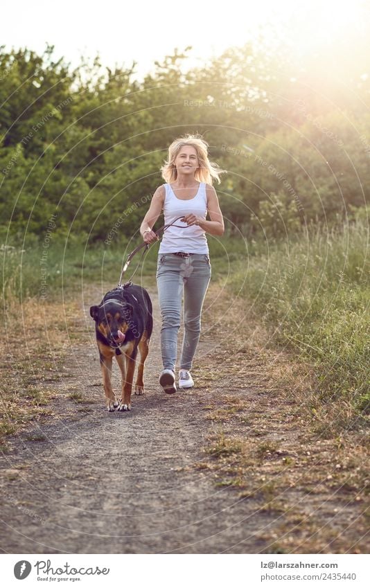 Glückliche Frau mittleren Alters, die mit ihrem Hund spazieren geht. Lifestyle schön Sommer Erwachsene Freundschaft 1 Mensch 45-60 Jahre Natur Tier Wärme Gras