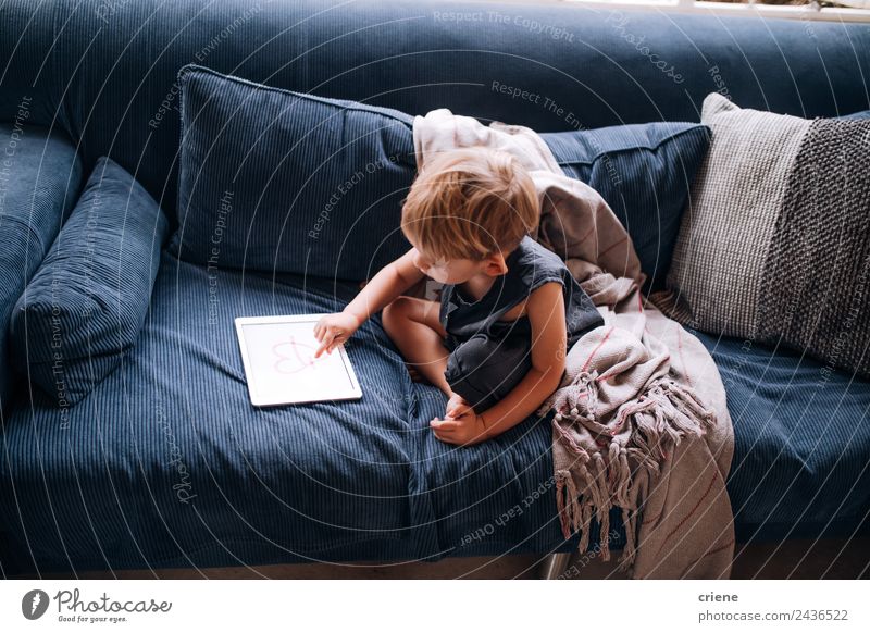 kleiner kaukasischer kleiner Junge spielt mit dem Tablett auf der Couch. Freude schön Spielen Sofa Wohnzimmer Kind Computer Bildschirm Technik & Technologie