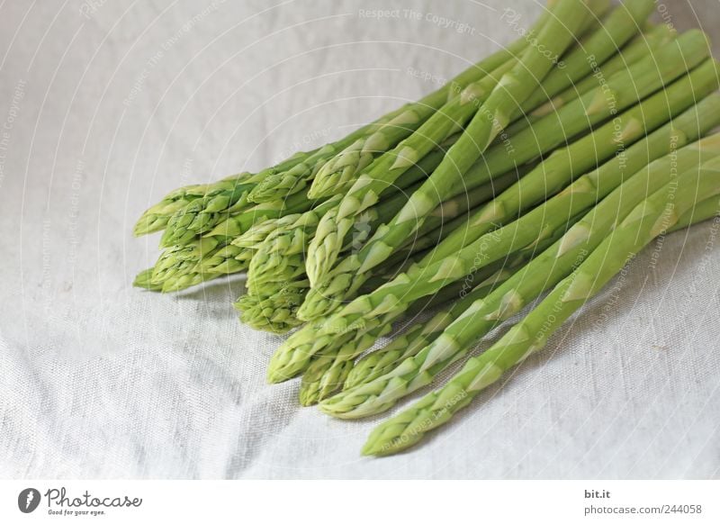 Portion Spargelbund mit grünem, frischem, saftigem Spargel, aus frischer, einheimischer Ernte, liegt als Haufen, Bündel auf einem weißem Tuch aus Leinen.