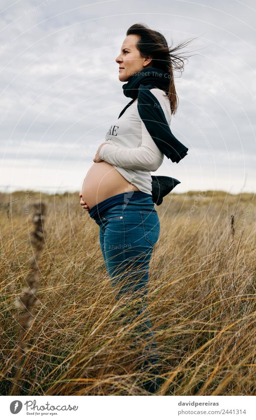 Schwangere Frau, die ihren nackten Bauch streichelt. Lifestyle Mensch Baby Erwachsene Mutter Familie & Verwandtschaft Natur Landschaft Horizont Wind Gras Wiese