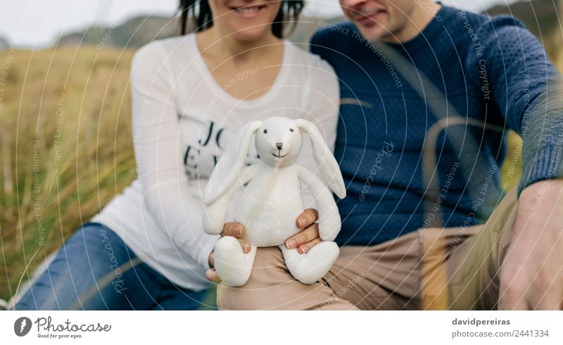 Ein Paar, das einen ausgestopften Hasen zeigt. Lifestyle Glück Mensch Baby Frau Erwachsene Mann Vater Familie & Verwandtschaft Gras Wiese Teddybär Lächeln Liebe
