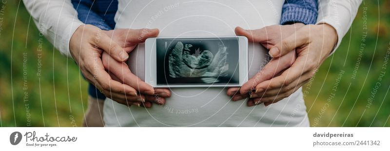 Mann zeigt Ultraschall über den Bauch seiner Frau. Lifestyle Leben PDA Technik & Technologie Mensch Baby Erwachsene Eltern Mutter Paar Hand authentisch