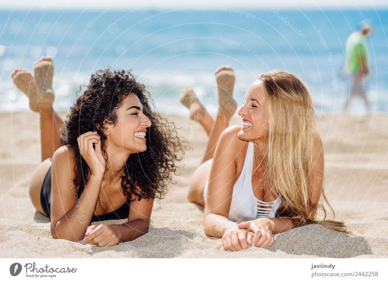Zwei Frauen, die auf dem Sand am Strand liegen. Lifestyle Freude Haare & Frisuren Ferien & Urlaub & Reisen Sommer feminin Junge Frau Jugendliche Erwachsene