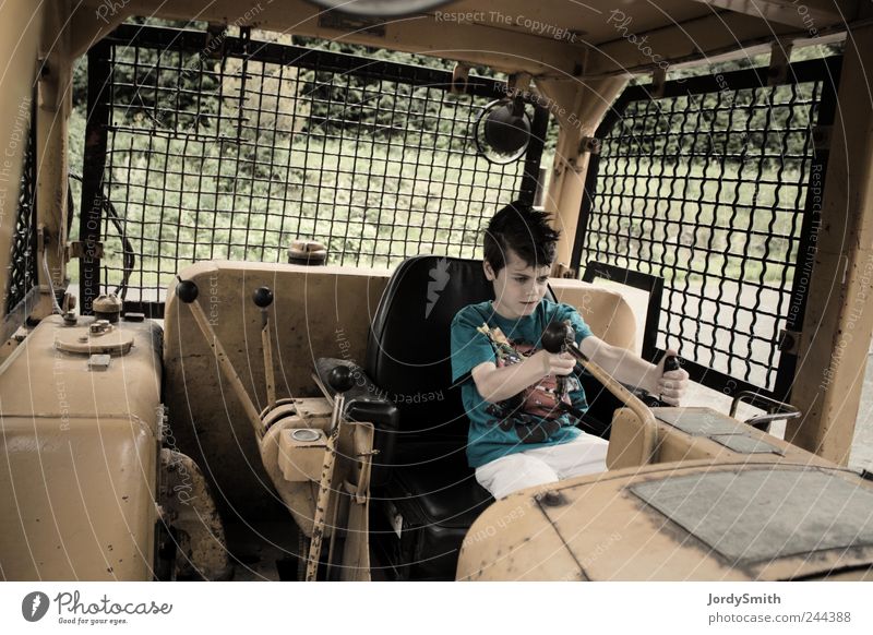 Der Junge in der mächtigen Maschine Baumaschine Mensch Kind 1 8-13 Jahre Kindheit Fahrzeug Baufahrzeug sitzen Spielen gelb Freude Selbstständigkeit fahren