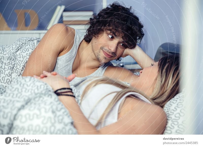 Mann schaut auf eine schöne Frau, die auf dem Bett liegt. Lifestyle Glück Erholung Schlafzimmer Erwachsene Familie & Verwandtschaft Paar Lächeln Liebe schlafen