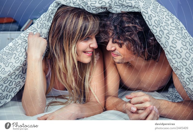 Glückliches junges verliebtes Paar lächelnd unter dem Bettbezug Lifestyle schön Erholung Schlafzimmer Frau Erwachsene Mann Familie & Verwandtschaft Küssen