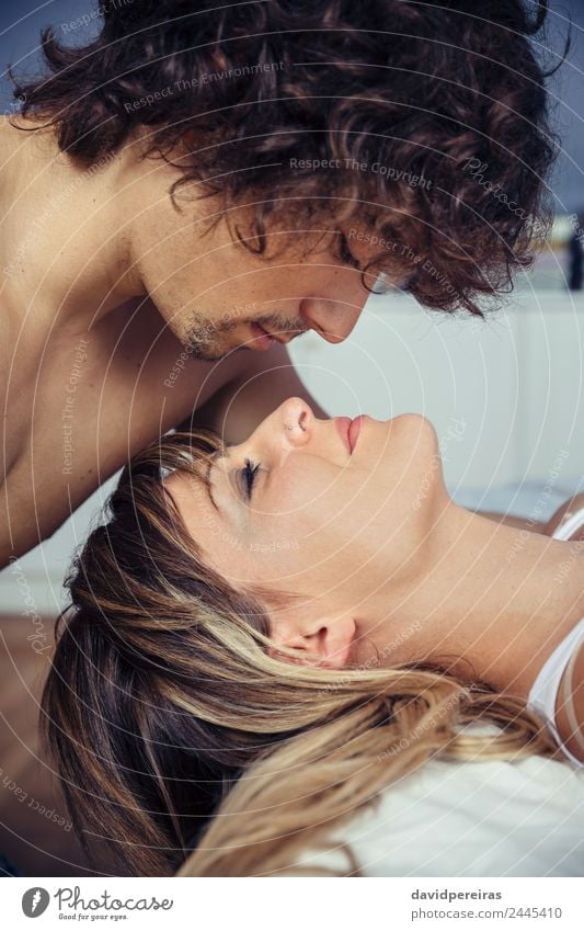 Junger Mann küsst die schöne Frau, die auf dem Bett liegt. Lifestyle Erholung Schlafzimmer Erwachsene Familie & Verwandtschaft Paar Küssen Liebe schlafen Sex