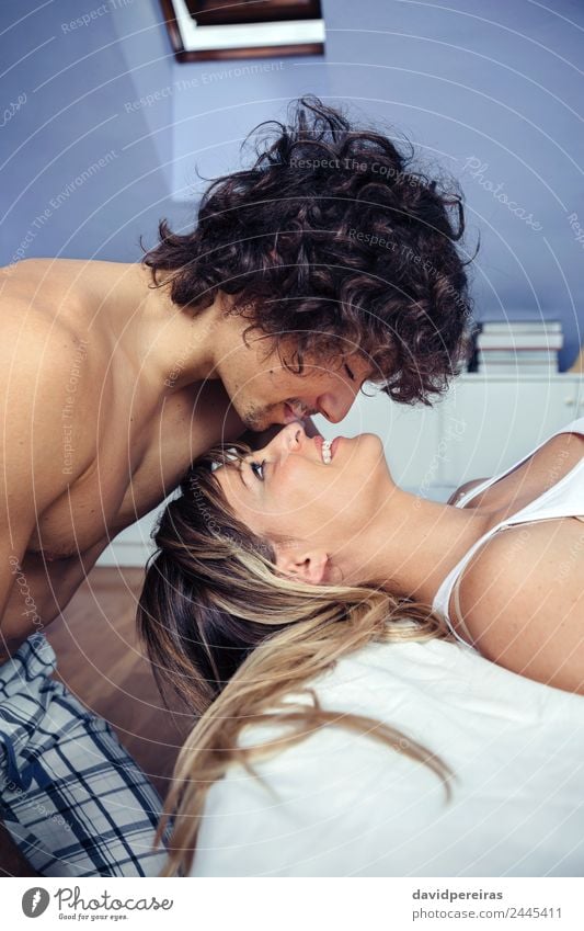 Junger Mann küsst die schöne Frau, die auf dem Bett liegt. Lifestyle Glück Erholung Schlafzimmer Erwachsene Familie & Verwandtschaft Paar Küssen Liebe schlafen