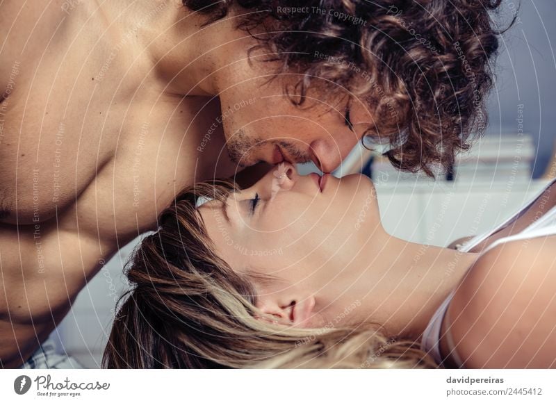 Junger Mann küsst auf schöne Frau über einem Bett liegend Lifestyle Glück Erholung Schlafzimmer Erwachsene Familie & Verwandtschaft Paar Küssen Liebe schlafen