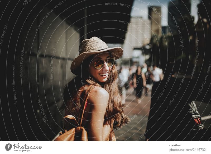 Glückliche Frau mit Sonnenbrille und Hut geht durch die Straßen von Sydney und schaut zurück in die Kamera. Lifestyle kaufen Stil Freizeit & Hobby