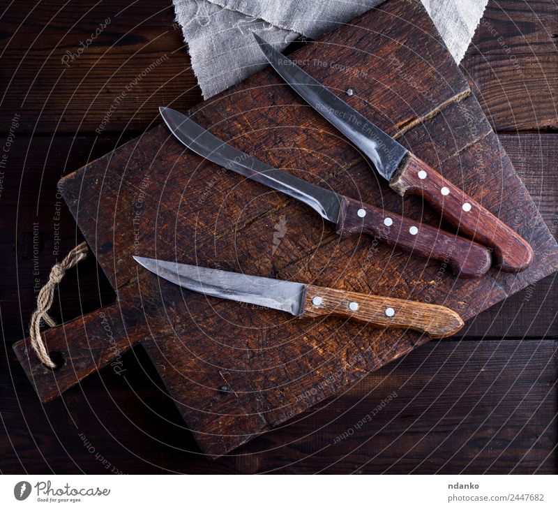drei alte Küchenmesser Messer Tisch Werkzeug Holz Metall Stahl braun Hintergrund Holzplatte Lebensmittel stechend Klinge Vorbereitung rostfrei professionell