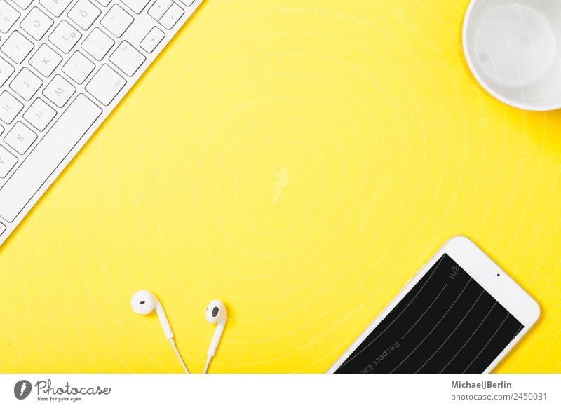 Handy und Kopfhörer auf gelbem Hintergrung Tasse Büro Tastatur Fröhlichkeit Hintergrundbild clever Symbole & Metaphern Arbeit & Erwerbstätigkeit Farbfoto