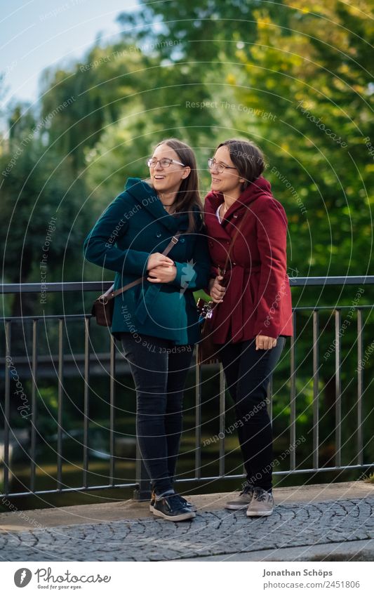 fröhliche Zwillingsschwestern stehen auf einer Brücke und schauen nach oben Lifestyle Stil Freude Glück Mensch feminin Junge Frau Jugendliche Geschwister