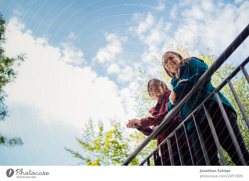 fröhliche Zwillingsschwestern stehen auf einer Brücke und schauen nach unten Lifestyle Stil Freude Glück Mensch feminin Junge Frau Jugendliche Geschwister