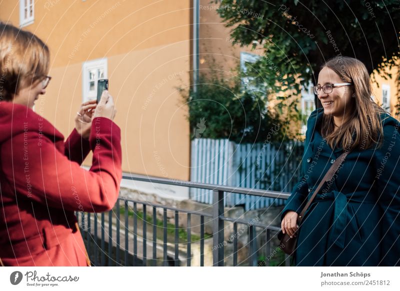 Zwillingsschwestern fotografieren sich gegenseitig mit Smartphone an einem Brückengeländer Lifestyle Stil Freude Glück Mensch feminin Junge Frau Jugendliche