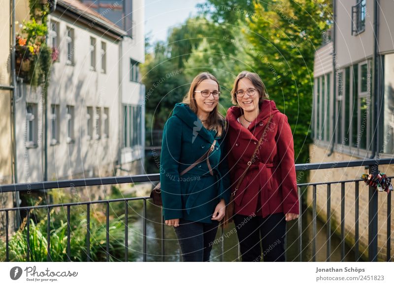 fröhliche Zwillingsschwestern stehen auf einer Brücke in Erfurt und lachen in die Kamera Lifestyle Stil Freude Glück Mensch feminin Junge Frau Jugendliche