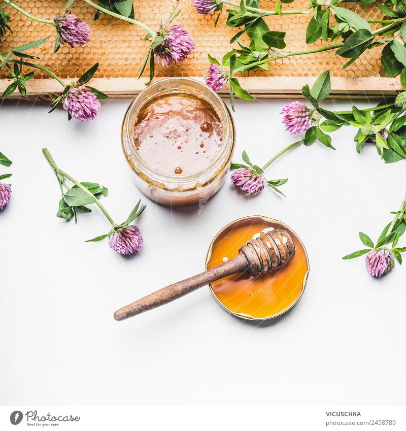 Honig in Glas mit Honigwabe und Blüten Lebensmittel Dessert Ernährung Bioprodukte Diät Geschirr Löffel Stil Design Behandlung Alternativmedizin