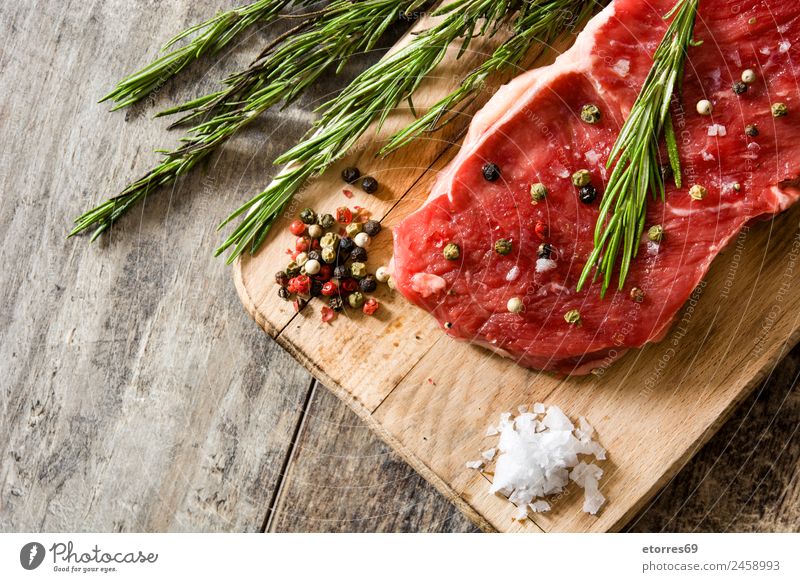 Rohes Rindfleischsteak mit Gewürzen, fertig zum Kochen auf Holztisch Lebensmittel Fleisch Ernährung Essen Mittagessen Abendessen grün rot roh Steak