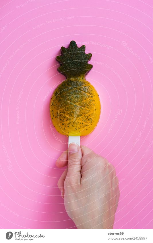 Hand mit Ananasstiel auf rosa Hintergrund. Draufsicht Lebensmittel Dessert Speiseeis Süßwaren Bioprodukte gelb Sommer Frucht Eis Snack kalt Tiefkühlkost Bonbon