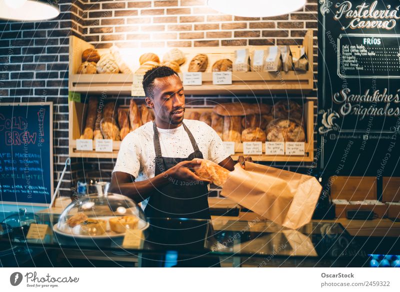 Der Afrikaner arbeitet in der Konditorei. Brot Tafel Arbeit & Erwerbstätigkeit Beruf Business Mensch Mann Erwachsene Lächeln stehen verkaufen Fröhlichkeit