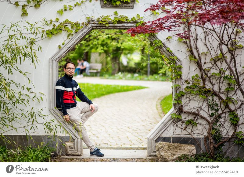 Prtrait eines jungen Mannes in einem Durchgang Tag 1 Mensch Junger Mann Porträt Deutschland Berlin Hauptstadt Natur Ahorn Ahornblatt Asien Japanischer Garten